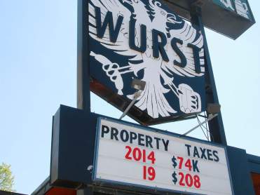 Wurst restaurant in Calgary, with sign: ‘PROPERTY TAXES – 2014, $74K – 2019, $208K’